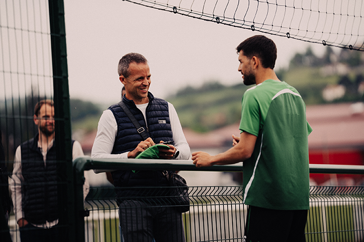 Échange convivial entre un membre de l’équipe et un joueur dans une ambiance sportive et professionnelle.
